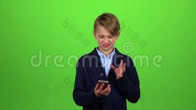 孩子用大拇指指着手机上的照片.. 绿色屏幕。 慢动作