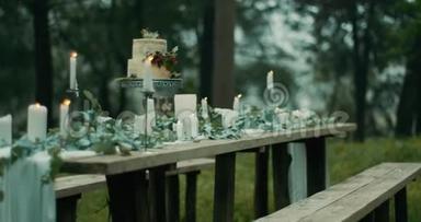 在雾蒙蒙的森林里提供浪漫晚餐的桌子。<strong>精美</strong>的装饰细节：树叶、花朵、<strong>蜡烛</strong>和双层
