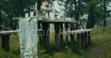 在雾蒙蒙的森林里约会的美妙装饰。 桌子上摆满了蜡烛、灯、花、蜡烛和两层
