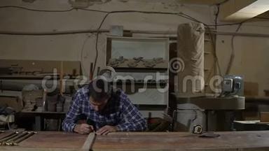 工作衫工人在工作台上用黄色长尺测量木板