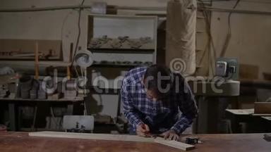 工作衫工人在工作台上用黄色长尺测量木板
