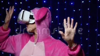 穿着粉红色睡衣的女孩kigurumi穿着黑色<strong>背景</strong>的VR眼镜。 帕贾马<strong>党</strong>