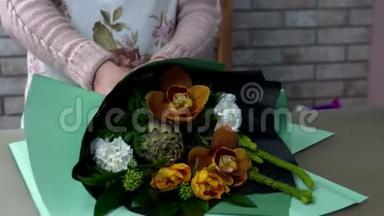 把花店里的花束用绿色包装纸包好。 菊芋，橙兰，白色康乃馨，脱脂。