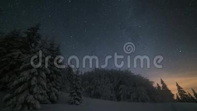 圣诞节的冬夜风景，星空在白雪皑皑的树木上移动。 天文时间流逝放大