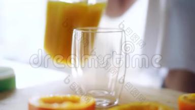 女人把橙汁从玻璃瓶里倒入玻璃杯里。 关上玻璃