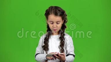 孩子用大拇指指着手机上的照片.. 绿色屏幕。 慢动作