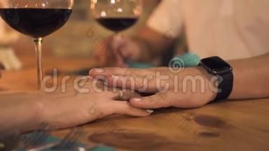 男手抚摸女手，晚上在餐厅浪漫约会。 女人在桌上摸着手的女朋友