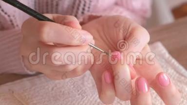 女人用小刷子把第<strong>二层</strong>粉红色的紫胶涂在指甲上。 特写双手。