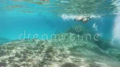 一位身穿<strong>黑色比基尼</strong>的年轻美女，带着面具和浮潜，在蓝色的水里游泳，动作缓慢
