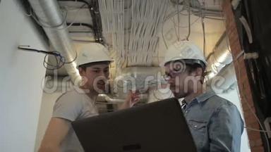 <strong>两个</strong>戴着头盔的建筑师在谈论着站在建筑工地上的笔记本<strong>电脑</strong>。 专家手提<strong>电脑</strong>。