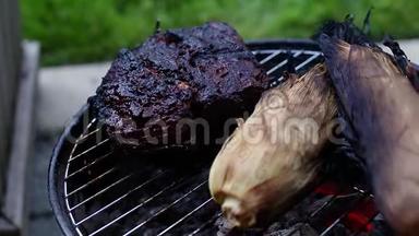 一个巨大的<strong>牛腩</strong>和玉米在一个小的木炭烤架上烤着，里面有燃烧的煤