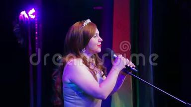 年轻的红发歌手用专业灯光在舞台上演唱