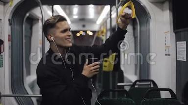 戴耳机听音乐和乘坐<strong>公共交通工具</strong>跳舞的帅哥的肖像.. 他握着扶手