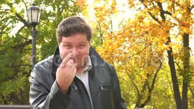 秋天公园里，一个微笑的胖子用手指向我们展示更近的姿态