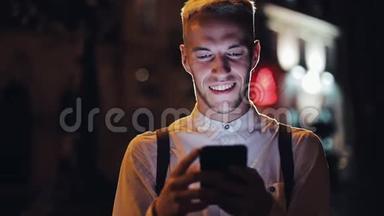 年轻有魅力的男人用智能<strong>手机</strong>站在夜城的街道上。 交流、旅游、旅游、<strong>约会</strong>、商务