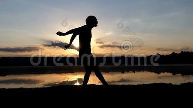 在日落时分，一个虔诚的人在湖岸跳着风格的舞蹈