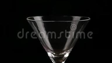 酒精在黑暗的背景上倒入玻璃杯中。 准备鸡尾酒和派对概念。 慢动作