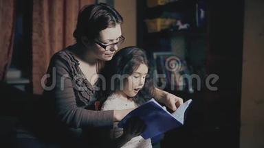 小女孩和一个成年女人正在读一本书，他们在晚上被教一个<strong>睡前</strong>故事。 母亲和