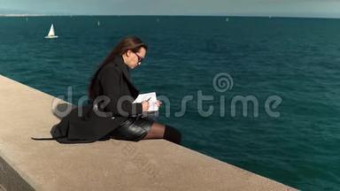 女人在海边的户外素描书上画素描。 慢镜头