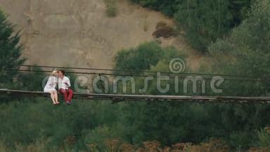 这对幸福相爱的旅行者正坐在河对岸挂着的木桥上接吻。 医生