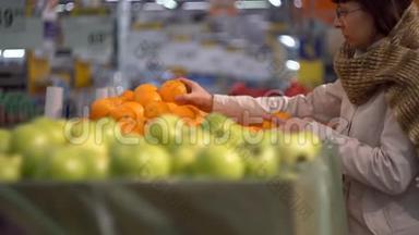 一个女孩在商店的<strong>蔬菜货架</strong>上选择橘子。