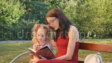 小可爱的女儿，有两个小辫子，和她的母亲戴着眼镜，坐在公园的长凳上看书。