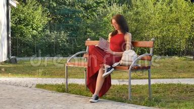 漂亮的女学生，戴着眼镜，穿着红<strong>长</strong>衣，坐在公园的<strong>长</strong>凳上，在公园里写<strong>东西</strong>