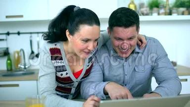 白人夫妇在厨房用电脑。 家庭、技术和<strong>人际关系</strong>概念-微笑的夫妻