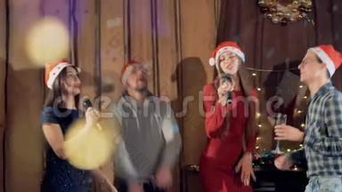 在新年晚会上，年轻人戴着圣诞帽跳舞唱歌。 慢动作。 4K.