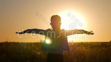 日落时分，金色田野里的小女孩幸福地举起双手。 美丽快乐小女孩剪影