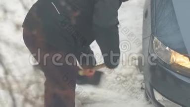 一个人从一辆<strong>被困</strong>在雪地里的车里挖了一铲雪