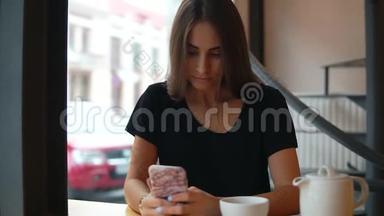 集中的年轻女士长发和自然化妆使用她的手机在咖啡店。 现代设备