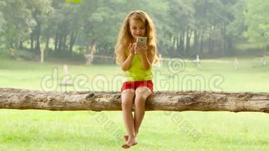 在美丽的夏日里，一个头发长长的小女孩<strong>坐在树上</strong>玩智能手机