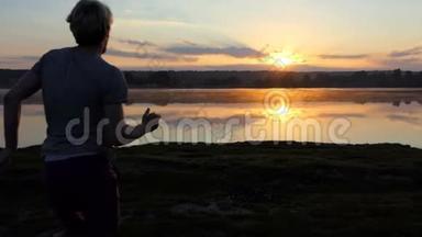 一个年轻的男子跑到森林湖在一个灿烂的日落在斯洛文尼亚