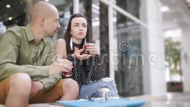 男人和女人在街头咖啡馆喝茶，看智能手机上的照片