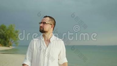 一个穿着宽松衬衫的年轻人沿着海滩散步。 在热带<strong>度假</strong>胜地<strong>度假</strong>