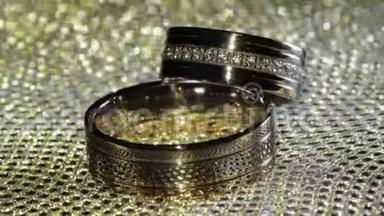 婚礼金戒指躺在闪亮的光泽表面。 光芒四射。 特写