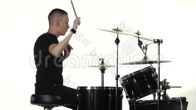 职业音乐家用棍子在鼓上演奏音乐。 白色背景。 侧视。 慢动作