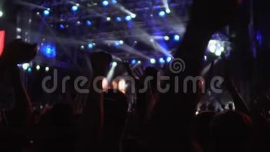 歌迷们在灯火通明的音乐厅挥舞双手跳舞的剪影