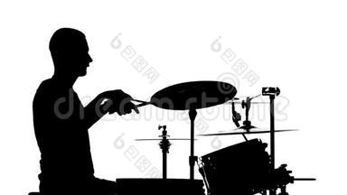 表演者在鼓上演奏专业音乐。 白色背景。 剪影。 侧视。 慢动作