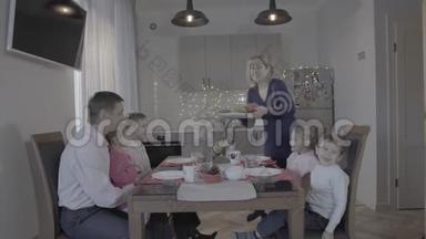 快乐的洛夫利四个孩子<strong>一家人</strong>在厨房餐桌上庆祝除夕，父亲，儿子，<strong>女儿</strong>，笑着，母亲在服侍着