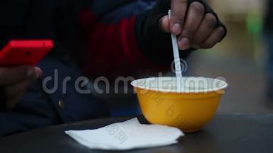 在寒冷的刮风天气里，有需要的人在户外吃热汤，体力劳动者的午餐