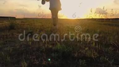 日落后拍摄的可爱少年女孩穿着连衣裙奔跑在绿色草地上。 120英尺，慢速运动。