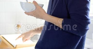 男子使用数码平板电脑，同时<strong>享用</strong>一碗早餐麦片