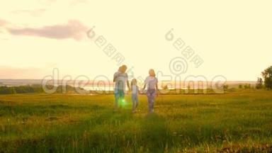 快乐的年轻家庭，有两个孩子在夏天的田野上奔跑。 健康的母亲、父亲和儿童享受大自然