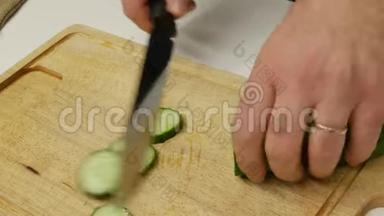 一个人切黄瓜做沙拉。 厨师正在切黄瓜片。