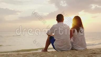 一男一女<strong>并排</strong>坐在沙滩上的沙滩上.. 他们一起<strong>看</strong>大海上的夕阳