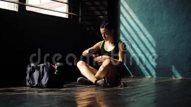 <strong>惊慌失措</strong>的年轻美女坐在地板上，用黑色拳击包裹在俱乐部里的手。