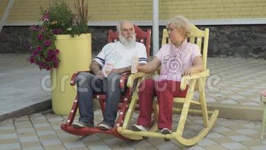 老人和老妇人在<strong>摇椅</strong>上休息，吃爆米花
