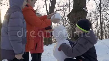 男孩子们在冬季公园<strong>堆雪人</strong>，慢镜头